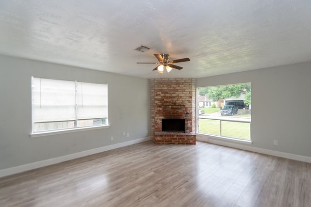 unfurnished living room featuring ceiling fan, plenty of natural light, light hardwood / wood-style flooring, and a textured ceiling