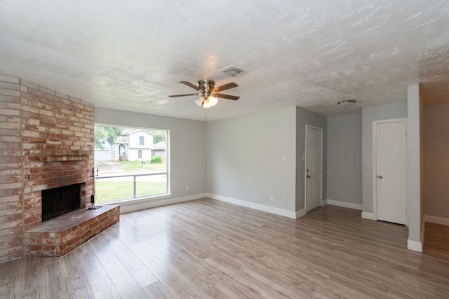 unfurnished living room featuring a textured ceiling, hardwood / wood-style flooring, ceiling fan, and a fireplace