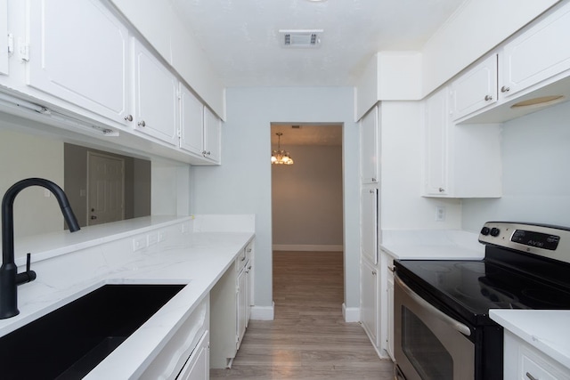 kitchen featuring stainless steel range with electric cooktop, light wood-type flooring, sink, white cabinets, and a chandelier