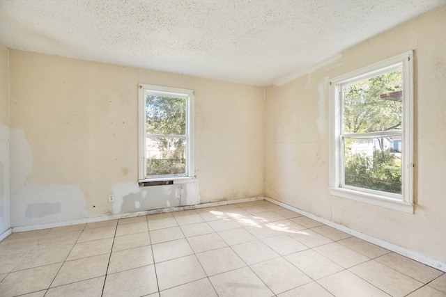 tiled spare room with a textured ceiling and a wealth of natural light