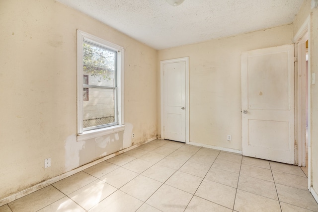 tiled spare room with a textured ceiling