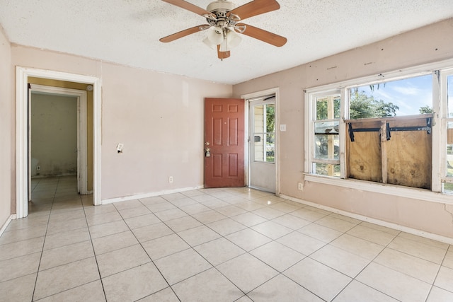 tiled empty room with ceiling fan and a textured ceiling