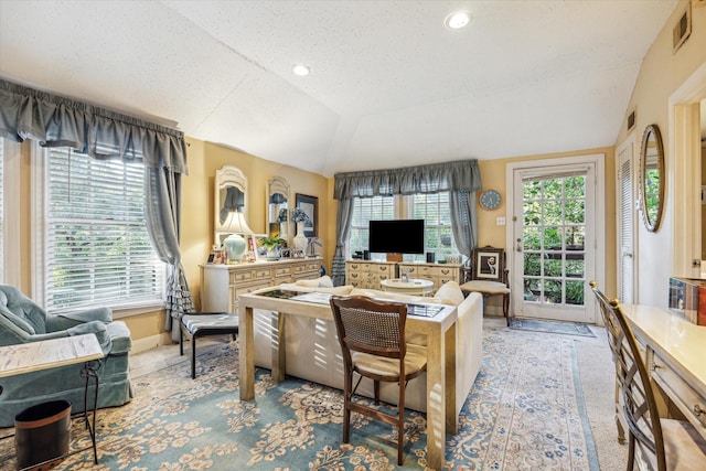 living area featuring light colored carpet, lofted ceiling, visible vents, and a textured ceiling