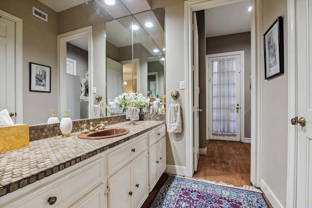 bathroom featuring wood finished floors, vanity, visible vents, and baseboards