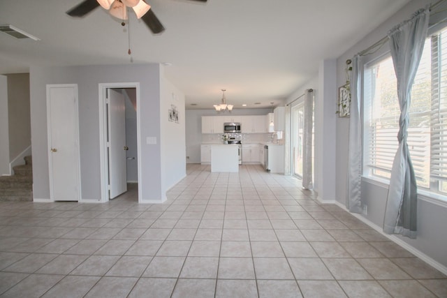 unfurnished living room with ceiling fan with notable chandelier and light tile patterned flooring