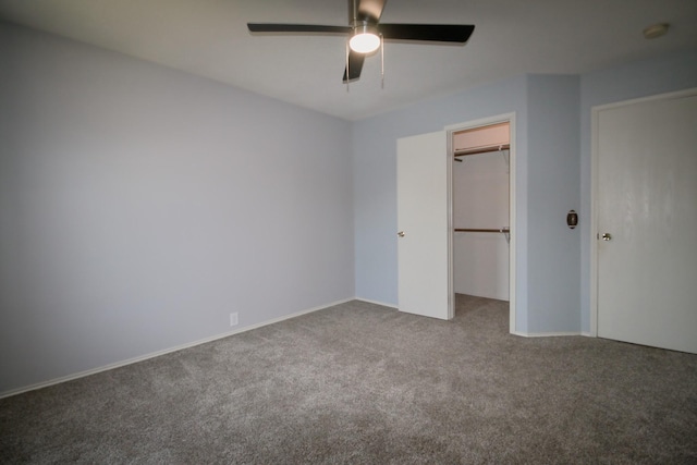 unfurnished bedroom featuring a closet, ceiling fan, a spacious closet, and carpet floors