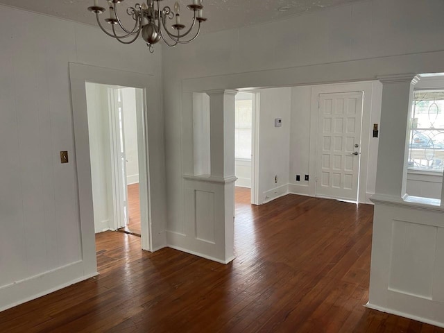 entryway featuring ornate columns, dark hardwood / wood-style floors, and an inviting chandelier