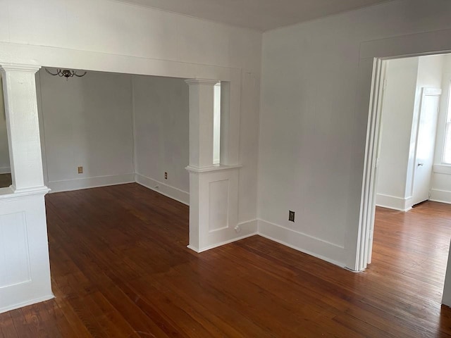 empty room with an inviting chandelier and dark hardwood / wood-style flooring