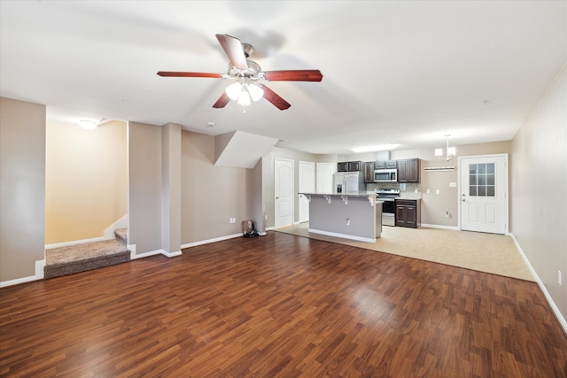 unfurnished living room featuring dark hardwood / wood-style floors and ceiling fan with notable chandelier