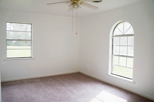 carpeted empty room featuring a healthy amount of sunlight and ceiling fan