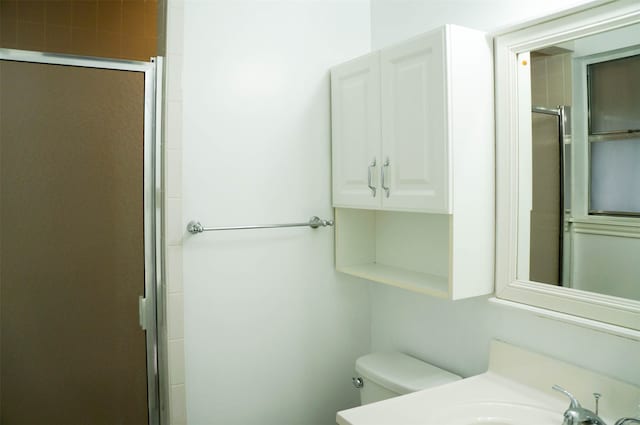 bathroom with a shower with door, sink, and toilet