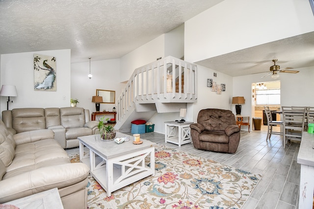 living room with ceiling fan, light hardwood / wood-style flooring, and a textured ceiling