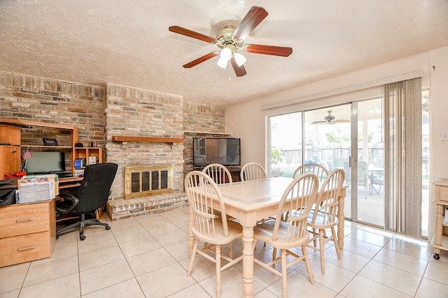 tiled dining room with a fireplace, ceiling fan, and a textured ceiling