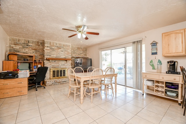 dining area with ceiling fan, a fireplace, light tile patterned floors, and a textured ceiling