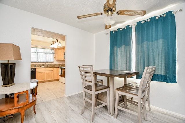 dining area featuring ceiling fan with notable chandelier, a textured ceiling, light wood-type flooring, and sink