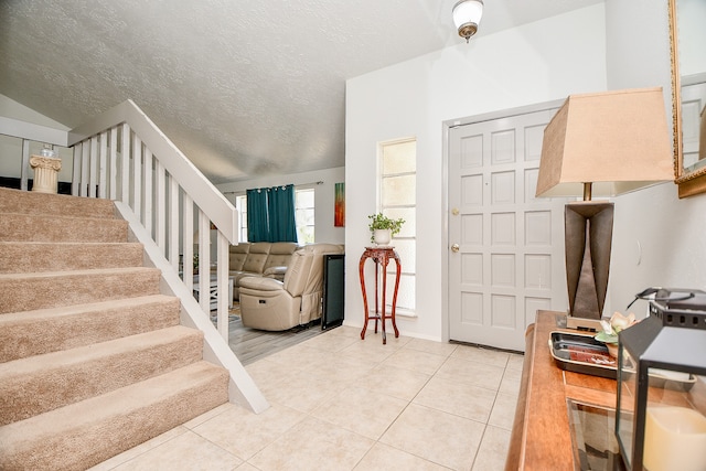 entryway featuring tile patterned flooring, lofted ceiling, and a textured ceiling