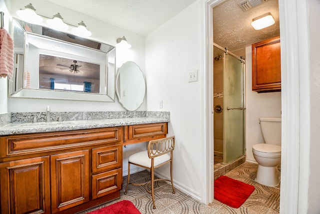 bathroom featuring vanity, a textured ceiling, toilet, and a shower with door