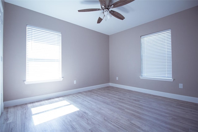 empty room with ceiling fan, wood-type flooring, and a wealth of natural light