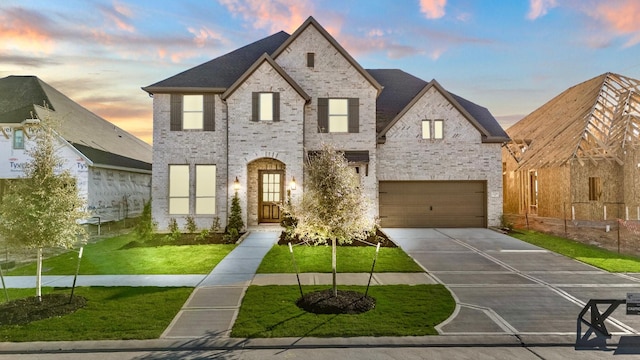 french country inspired facade featuring a lawn and a garage