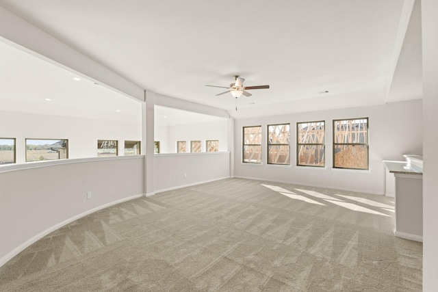 carpeted spare room featuring ceiling fan and a wealth of natural light