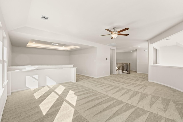 carpeted spare room with ceiling fan and a raised ceiling