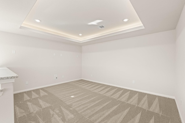 unfurnished room with carpet and a tray ceiling