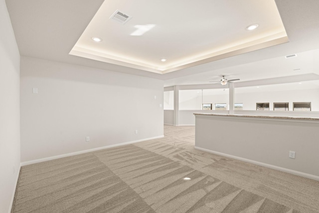 carpeted empty room with a tray ceiling and ceiling fan