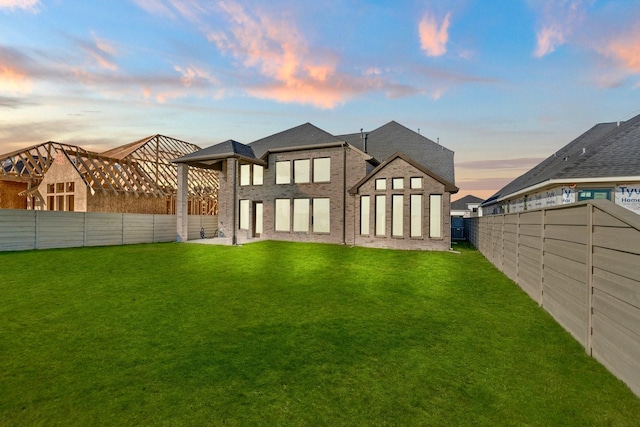 back house at dusk with a lawn