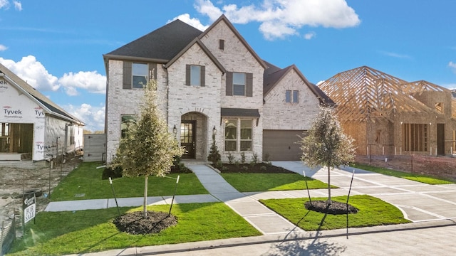 french country inspired facade featuring a garage and a front lawn