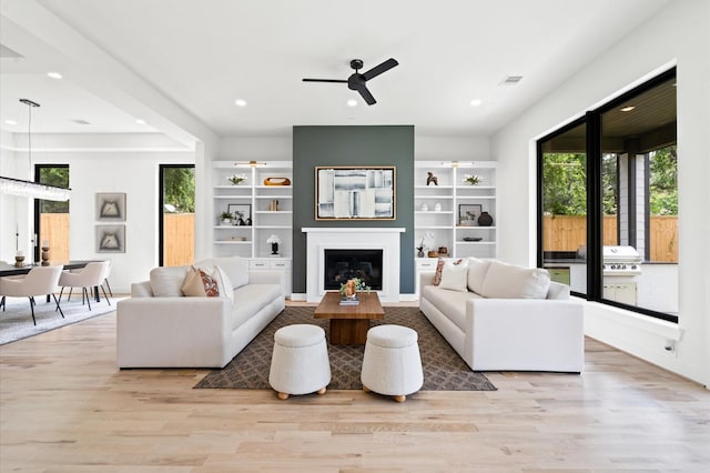 living room featuring ceiling fan, a fireplace, and light hardwood / wood-style flooring