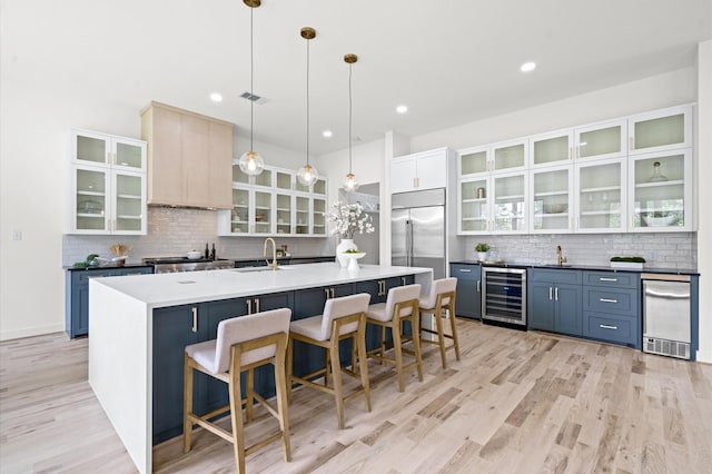 kitchen with stainless steel built in refrigerator, pendant lighting, wine cooler, and blue cabinets