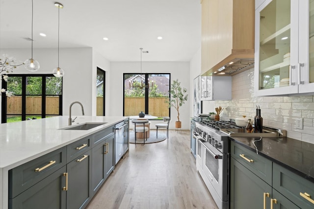 kitchen featuring sink, wall chimney exhaust hood, decorative backsplash, appliances with stainless steel finishes, and decorative light fixtures