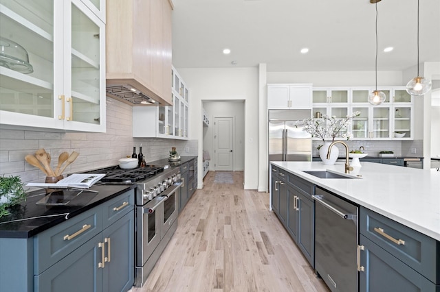 kitchen with white cabinets, blue cabinets, sink, appliances with stainless steel finishes, and decorative light fixtures