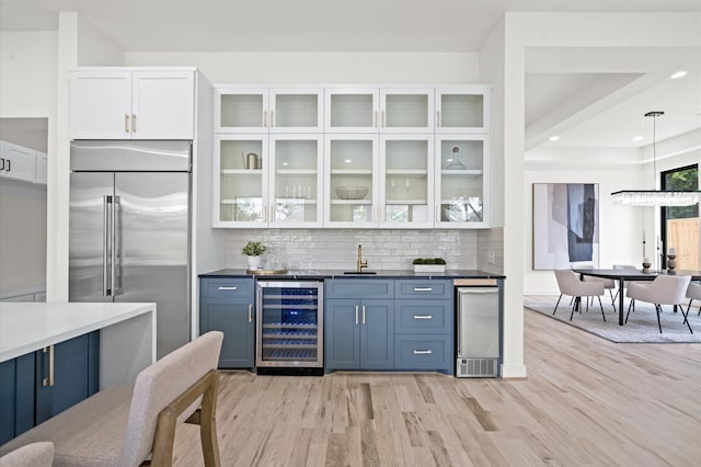 interior space featuring white cabinets, wine cooler, tasteful backsplash, decorative light fixtures, and stainless steel built in refrigerator