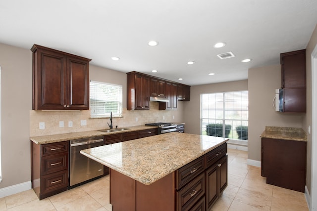 kitchen with light tile patterned floors, backsplash, stainless steel appliances, sink, and a center island