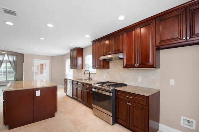 kitchen featuring backsplash, sink, a center island, appliances with stainless steel finishes, and light stone counters