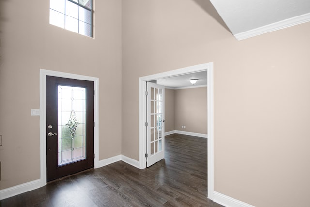 foyer entrance featuring dark wood-type flooring, crown molding, a towering ceiling, and french doors