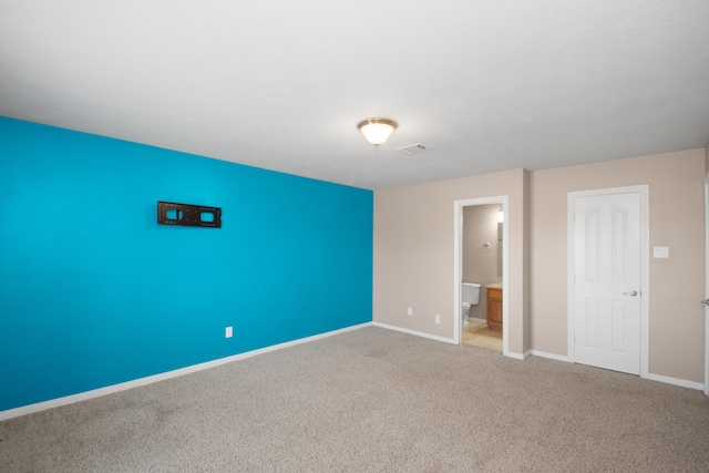 unfurnished bedroom featuring ensuite bathroom and carpet flooring