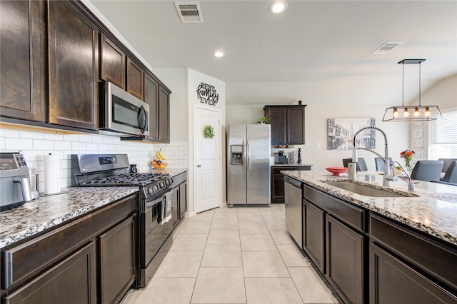 kitchen with dark brown cabinets, sink, pendant lighting, appliances with stainless steel finishes, and light stone counters