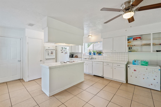 kitchen featuring tasteful backsplash, tile countertops, white cabinetry, light tile patterned flooring, and white appliances