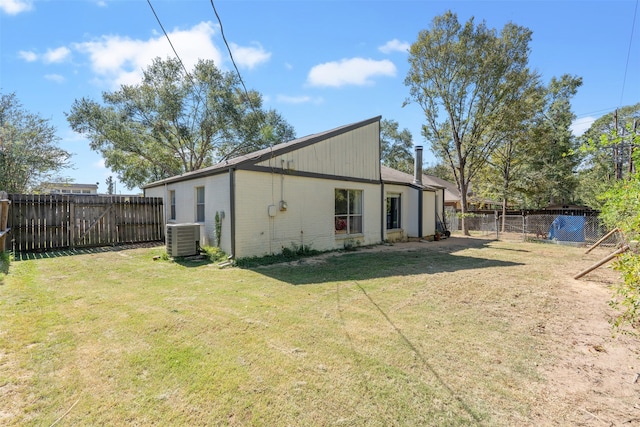 back of house featuring central air condition unit and a lawn