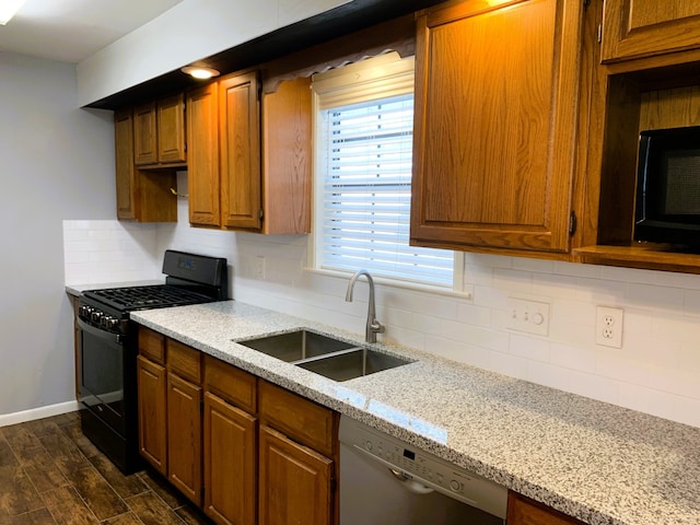 kitchen with sink, gas stove, white dishwasher, dark wood-type flooring, and light stone counters