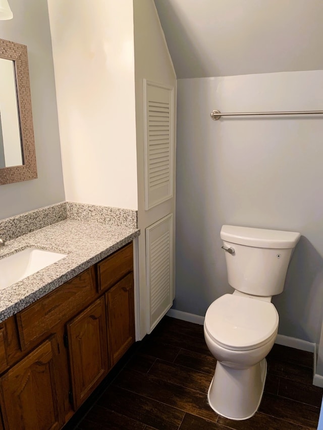 bathroom with vanity, vaulted ceiling, hardwood / wood-style flooring, and toilet