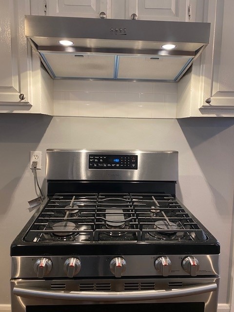 details featuring stainless steel gas range oven and white cabinets