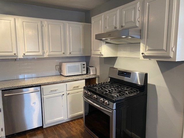 kitchen featuring white cabinets, stainless steel appliances, dark wood-type flooring, and backsplash