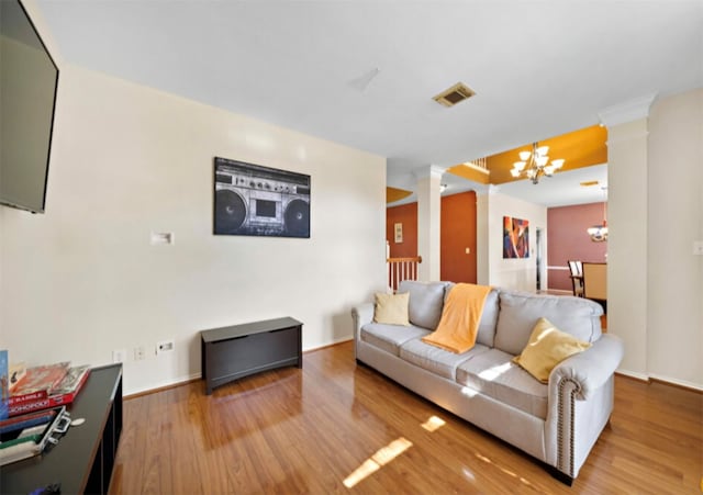 living room featuring a notable chandelier, hardwood / wood-style flooring, and ornate columns