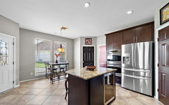 kitchen featuring a kitchen breakfast bar, stainless steel appliances, a center island, decorative light fixtures, and beverage cooler