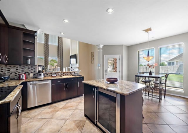 kitchen featuring a kitchen island, dishwasher, ornate columns, dark brown cabinetry, and decorative light fixtures