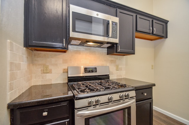 kitchen featuring backsplash, appliances with stainless steel finishes, and dark hardwood / wood-style flooring