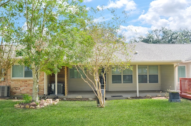 back of house with central AC and a lawn